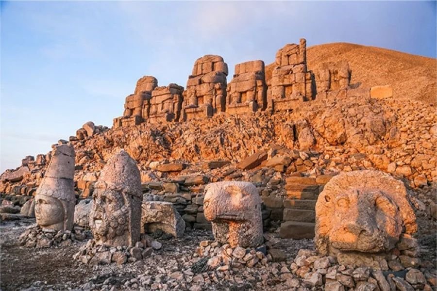 Adıyaman'daki Nemrut Dağı'nda gün batımı ışığıyla aydınlanmış, UNESCO Dünya Mirası listesindeki Kommagene Krallığı'na ait devasa tarihi kral ve tanrı heykellerinin kalıntıları.